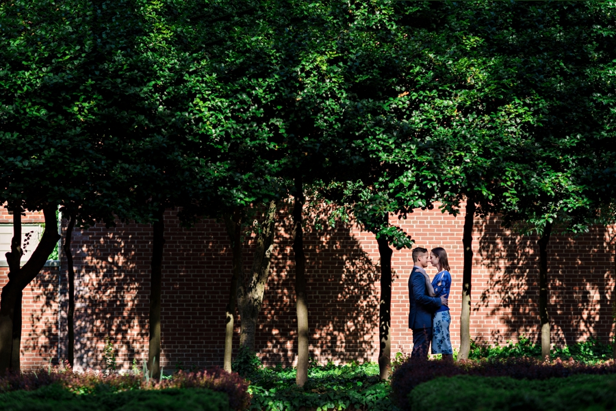 A couple kiss in between a tree lined walkway in philadelphia.